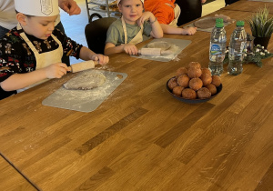 Dzieci wałkują ciasto na pierniczki.