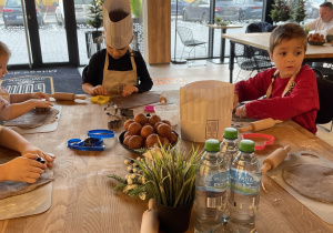 Dzieci wałkują ciasto na pierniczki.