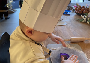 Dzieci wałkują ciasto na pierniczki.