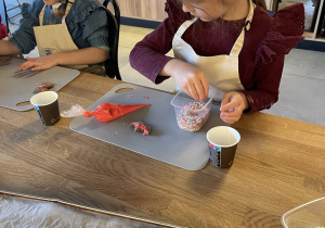 Dzieci dekorują pierniczki lukrem i kolorowymi posypkami.