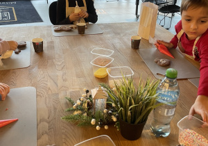 Dzieci dekorują pierniczki lukrem i kolorowymi posypkami.