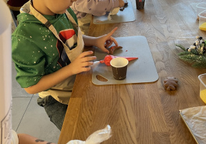 Dzieci dekorują pierniczki lukrem i kolorowymi posypkami.