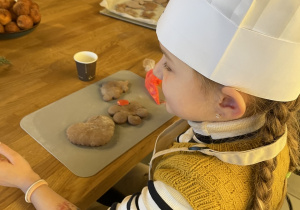 Dzieci dekorują pierniczki lukrem i kolorowymi posypkami.