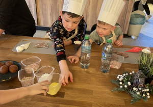 Dzieci dekorują pierniczki lukrem i kolorowymi posypkami.