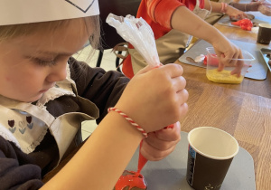 Dzieci dekorują pierniczki lukrem i kolorowymi posypkami.