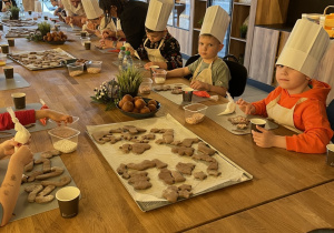 Dzieci dekorują pierniczki lukrem i kolorowymi posypkami.