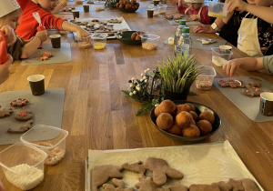 Dzieci dekorują pierniczki lukrem i kolorowymi posypkami.