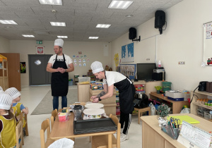 Rodzice przygotowują składniki potrzebna do pieczenia pizzy.