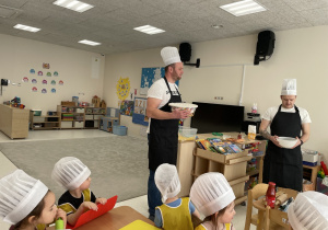 Tata Oliwierka prezentuje dzieciom wyrobione ciasto.