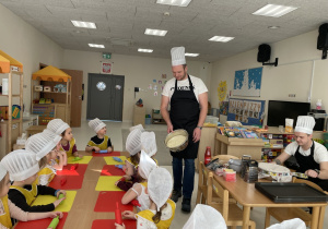 Tata Stasia pokazuje dzieciom gotowe ciasto na pizzę.