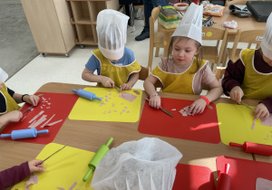 Dzieci kroją szynkę do pizzy.