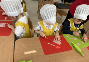 Dzieci kroją szynkę do pizzy.