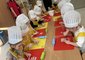 Dzieci kroją szynkę do pizzy.