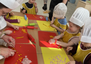 Dzieci kroją składniki do pizzy.