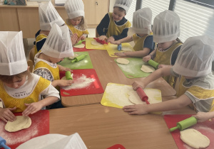 Dzieci wałkują ciasto na pizzę.