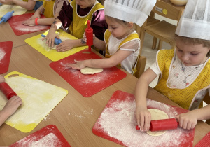 Dzieci wałkują ciasto na pizzę.