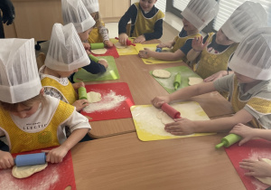Dzieci wałkują ciasto na pizzę.