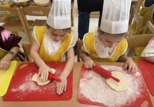 Dziewczynki wałkują ciasto.