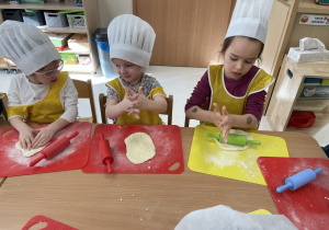 Dziewczynki wałkują ciasto.