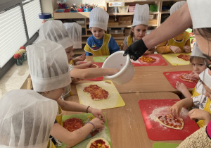 Dzieci wybierają składniki, które położą na swojej pizzy.