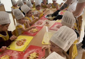 Dzieci wybierają składniki, które położą na swojej pizzy.