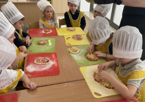 Dzieci wybierają składniki, które położą na swojej pizzy.