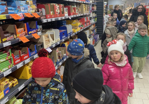 Dzieci oglądają sklepowe regały.