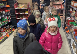 Dzieci oglądają produktu znajdujące się na sklepowych regałach.