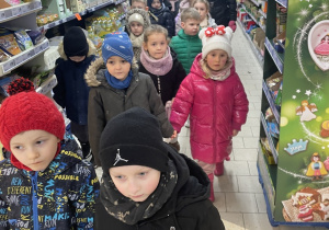 zieci oglądają produktu znajdujące się na sklepowych regałach.