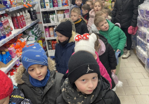 zieci oglądają produktu znajdujące się na sklepowych regałach.