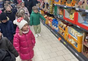 zieci oglądają produktu znajdujące się na sklepowych regałach.