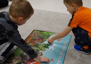 Chłopcy dopasowuje sylwetę dinozaura do konturu.