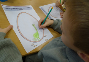 Chłopiec pokazuje rysunek swojego dinozaura.