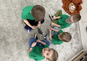 Dzieci przypinają klamerki do dinozaura według odpowiedniej kolejności.