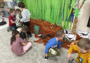 Dzieci podczas wspólnych zabaw dinozaurami przyniesionymi z domu.