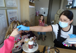 03 Pani kosmetyczka pokazuje wzorniki z kolorowymi paznokciami