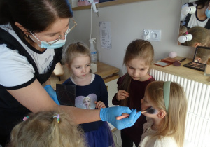 31 Pani kosmetyczka nakłada dziewczynkom róz na policzki