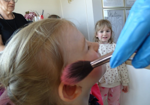 33 Pani kosmetyczka nakłada dziewczynkom róz na policzki