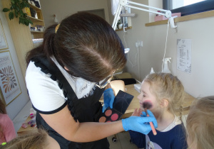 35 Pani kosmetyczka nakłada dziewczynkom róz na policzki