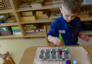 chłopiec przekłada pęsetą kulki