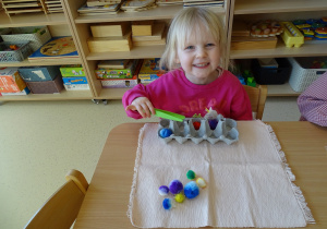 dziewczynka przekłada pęsetą kulki