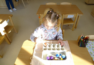 dziewczynka przekłada pęsetą kulki