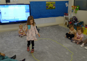 dziecko chodzi po elipsie z kubkiem wody