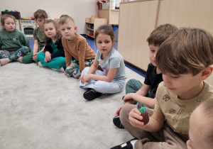 Dzieci w kole podają sobie jajo z dinozaurem