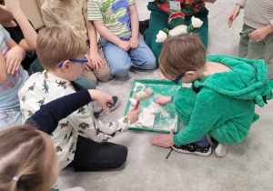 Dzieci w ochronnych okularach rozbijają skamielinę