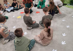 Pani rozkłada na podłodze ślady dinozaurów