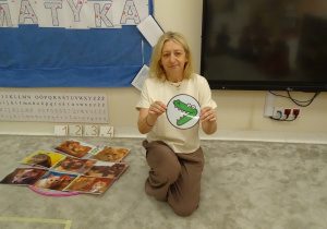 18 Pani pokazuje dzieciom znak matematyczny w postaci obrazka