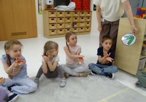 19 Pani pokazuje dzieciom znak matematyczny w postaci obrazka, dzieci pokazują go dłońmi