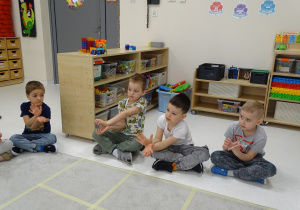 21 Pani pokazuje dzieciom znak matematyczny w postaci obrazka, dzieci pokazują go dłońmi