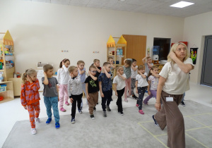 30 Dzieci z panią podczas zabawy muzyczno - ruchowej utrwalającej kierunki w przestrzeni i stronności własnego ciała